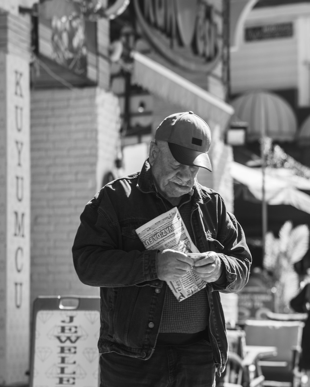 about-02 elderly-man-reading-a-newspaper-on-a-street-meienyduuy0