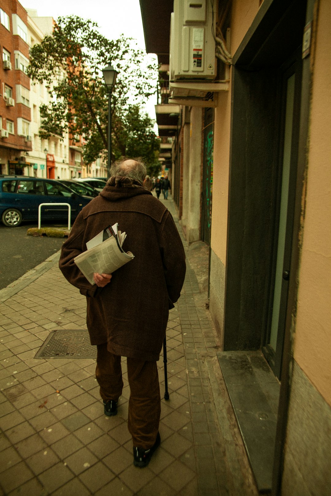 about-01 senior-man-walking-on-a-sidewalk-holding-a-newspaper-0irlb-fhj1w